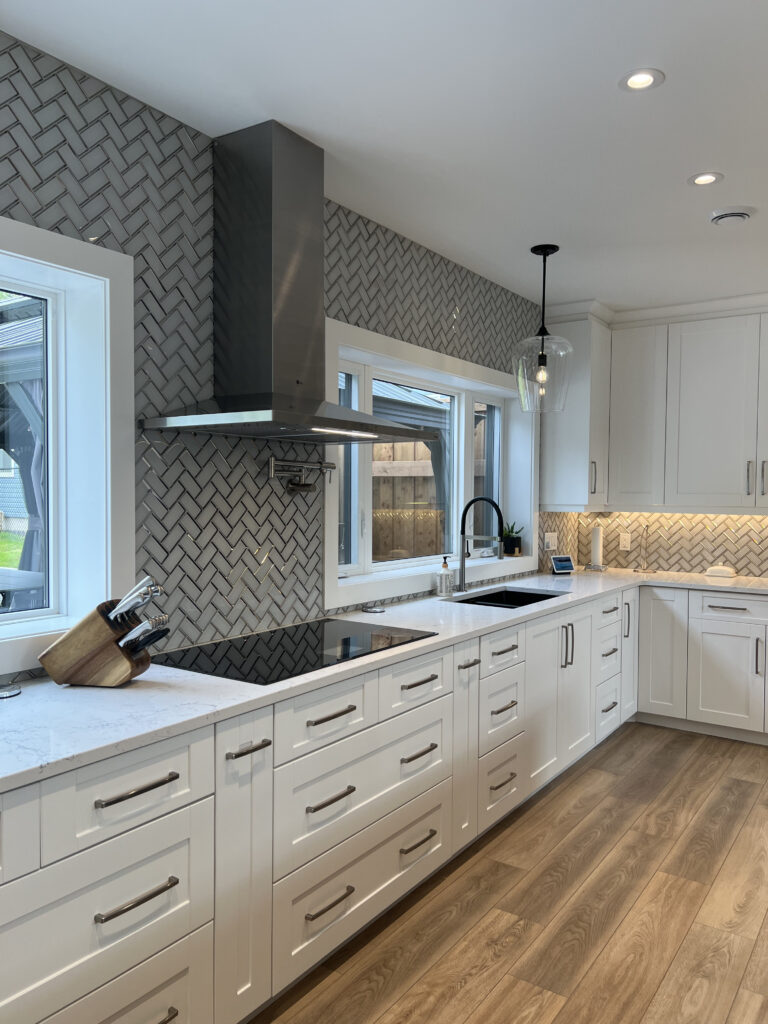 White painted Shaker kitchen cabinets with black accents and quartz countertops.